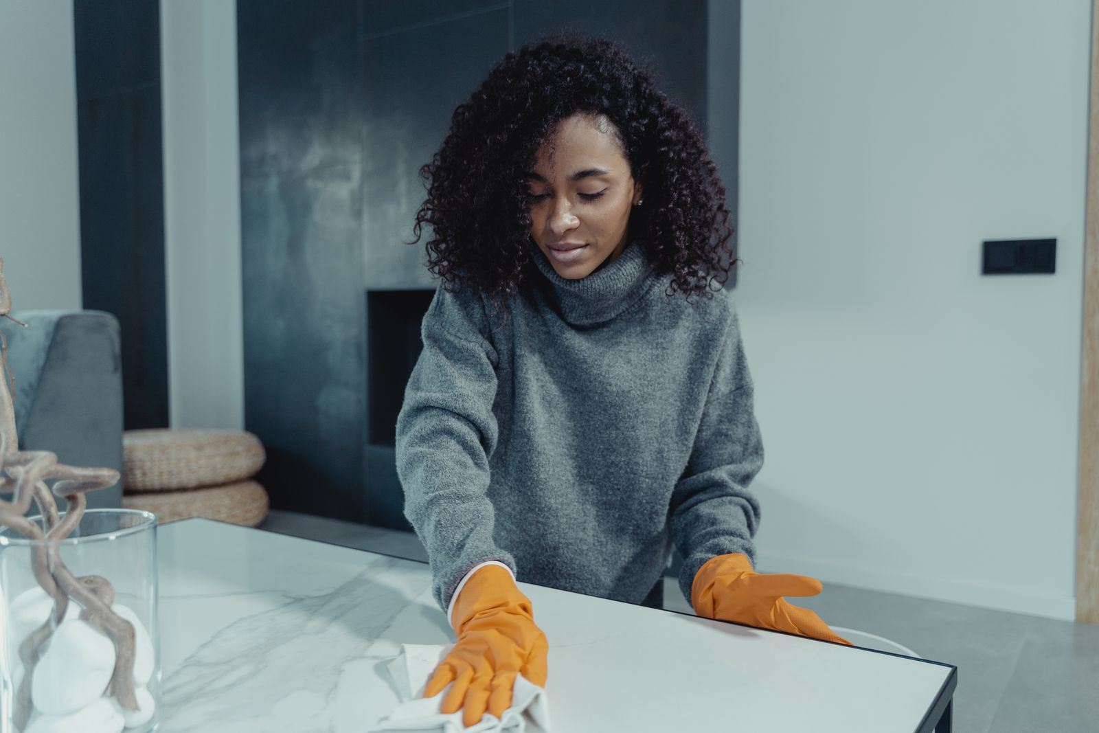 Mujer con guantes limpiando una mesa en un salón luminoso